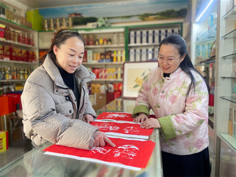 圖為顧客饒有興趣地觀看沈文瑩(右)的剪紙作品