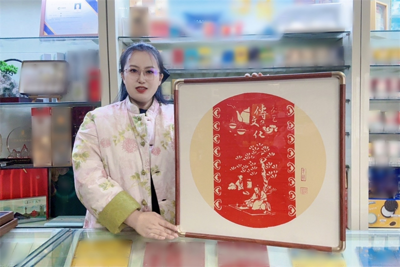 圖為沈文瑩和她創(chuàng)作的剪紙作品