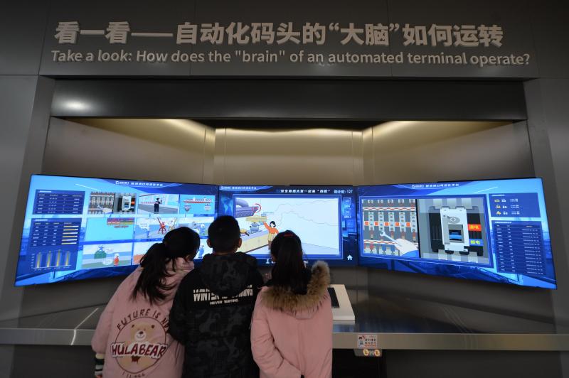 三名學(xué)生在體驗(yàn)自動(dòng)化碼頭“大腦”平臺(tái)。