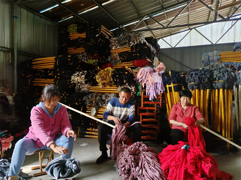 圖為村民們正在生產(chǎn)拖把