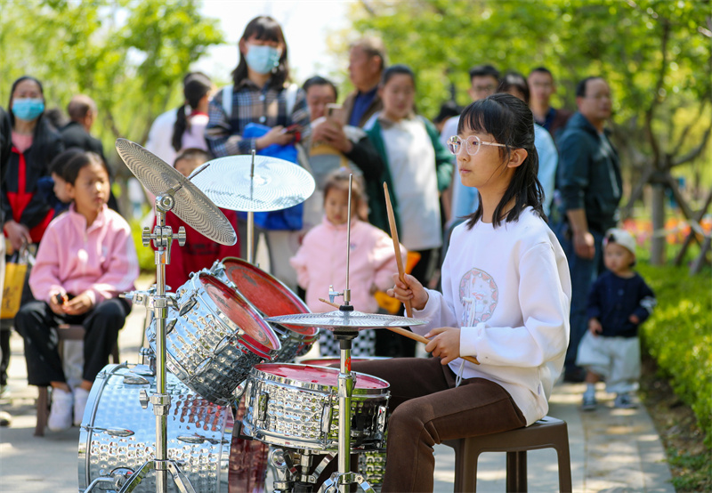 4月20日，一小朋友在山東青島萊西市月湖公園給游客表演架子鼓。張進剛攝