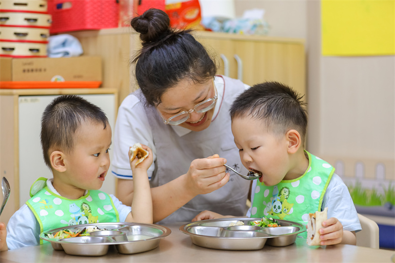 2025年5月14日，在山東省青島市李滄區(qū)職工子女愛(ài)心托育中心，老師教小朋友學(xué)吃飯。張鷹 攝 