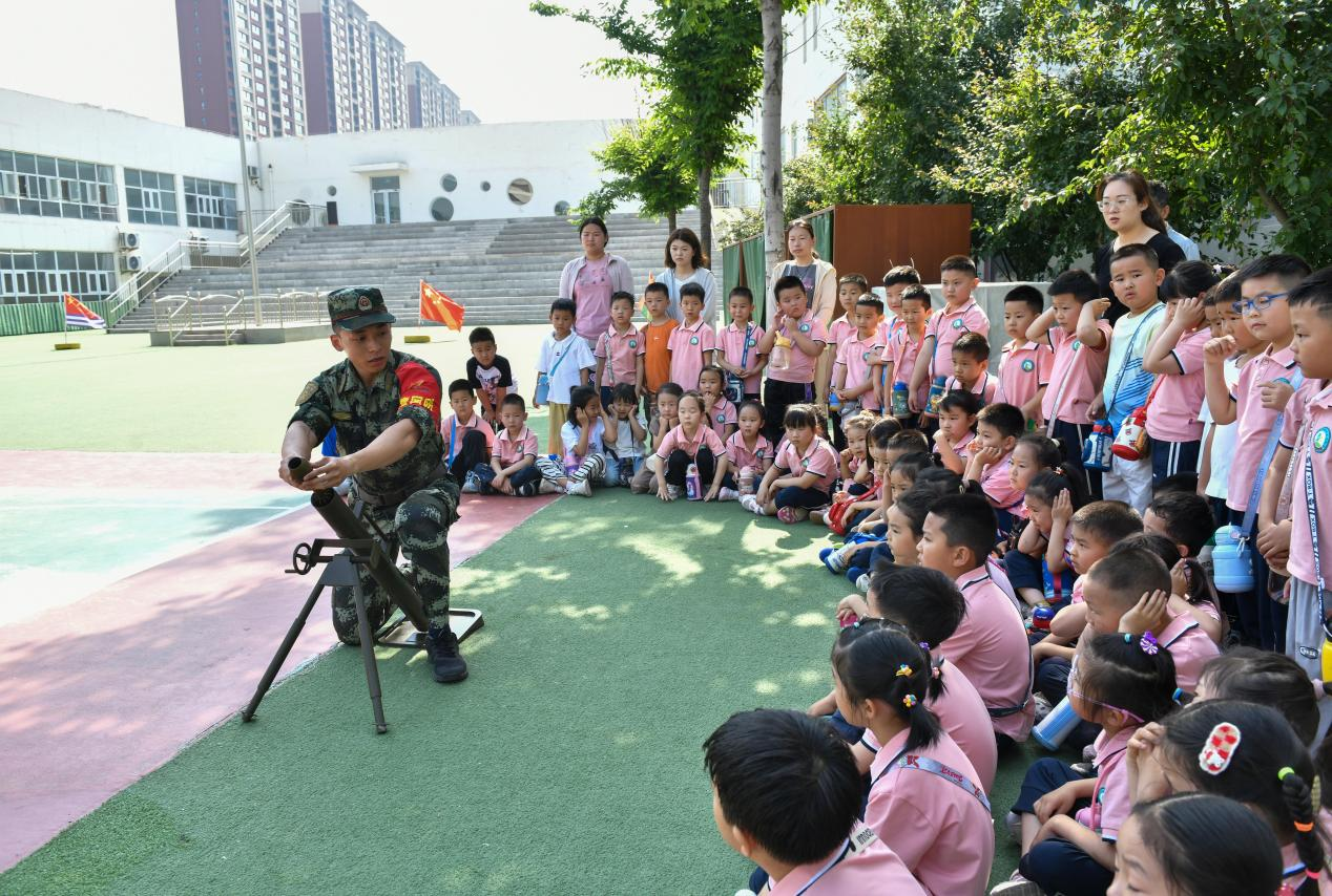 5月20日，在鄒平市全民國防教育進(jìn)校園活動中，工作人員為黃山實(shí)驗幼兒園幼兒講解軍事武器國防知識。