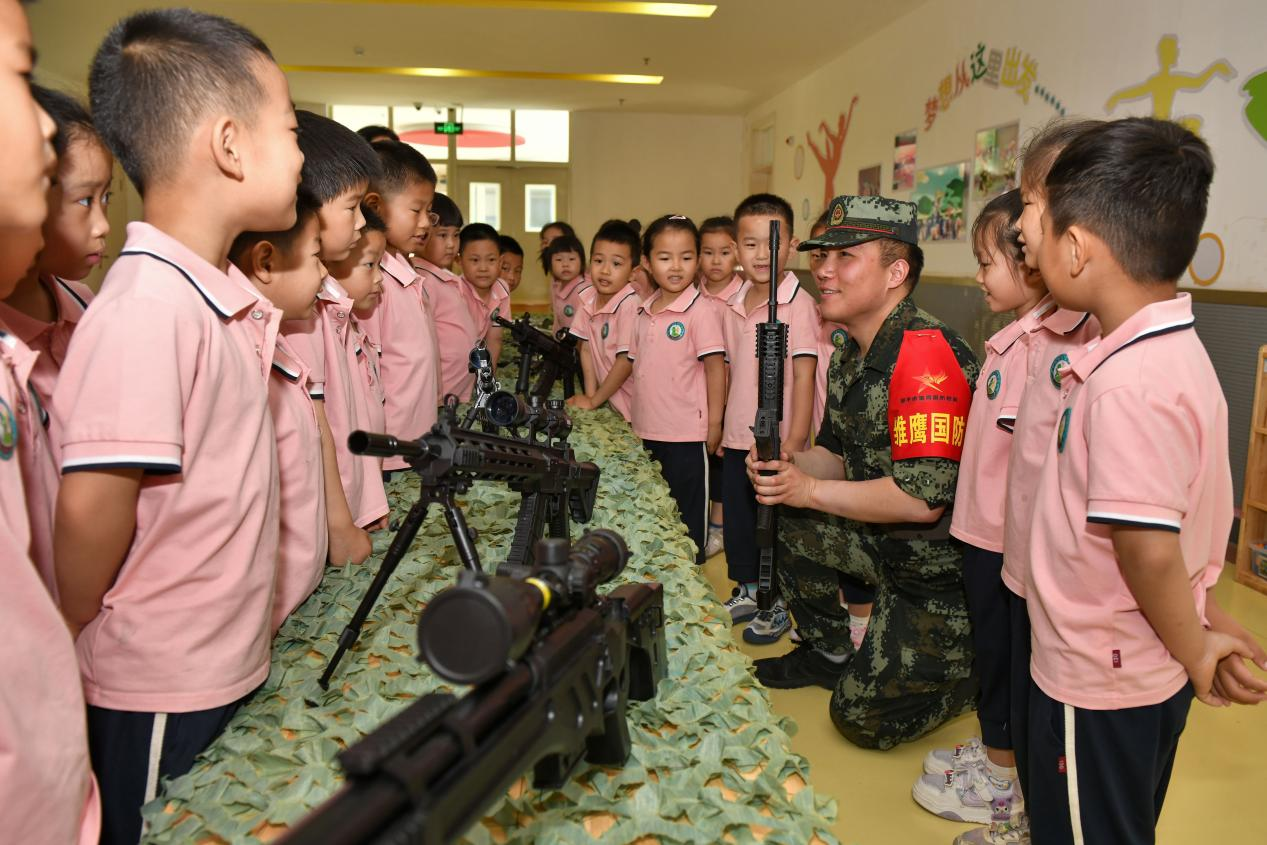5月20日，在鄒平市全民國防教育進(jìn)校園活動中，工作人員為黃山實(shí)驗幼兒園幼兒講解槍械知識。