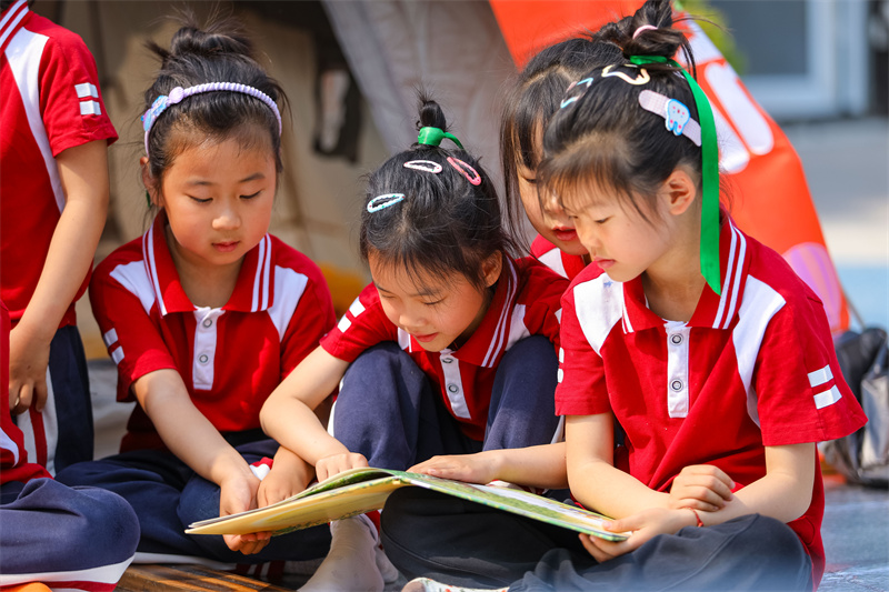 2025年5月26日，小朋友在山東省青島市李滄區(qū)青山路幼兒園開展迎“六一”主題活動中閱讀繪本故事。張鷹 攝