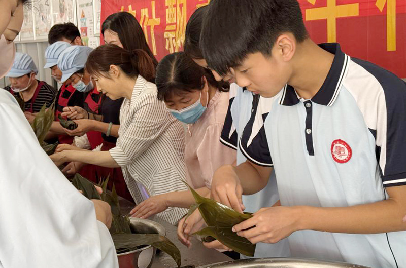 師生們圍在一起，體驗包粽子的樂趣。鄧璇攝