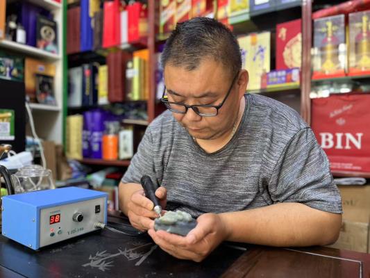 圖為宋濤在玉料上專(zhuān)心雕刻