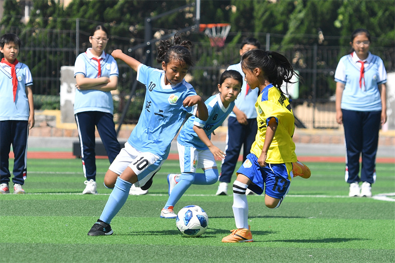 2025年6月23日，在山東省青島市市北區(qū)延安二路小學(xué)開展的“國(guó)際奧林匹克日”活動(dòng)上，學(xué)生們?cè)诰G茵場(chǎng)上進(jìn)行足球演練。