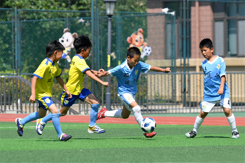 2025年6月23日，在山東省青島市市北區(qū)延安二路小學(xué)開展的“國(guó)際奧林匹克日”活動(dòng)上，學(xué)生們?cè)诰G茵場(chǎng)上進(jìn)行足球演練。