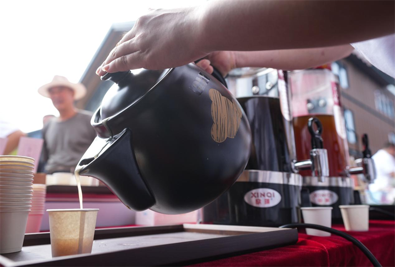 6月28日，在山東省鄒平市的夏季“黃河大集”養(yǎng)生市集，攤主為顧客準備營養(yǎng)粥。 