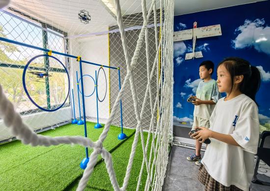 2025年7月22日，在山東省樂陵市市中街道碼高科技編程中心，孩子們?cè)诰毩?xí)無人機(jī)穿圈操作。