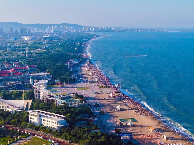 夏季的日照，湛藍大海與蔥郁綠植相映成趣，綿延沙灘上人潮如織，洋溢著活力與熱情。宋年升 攝