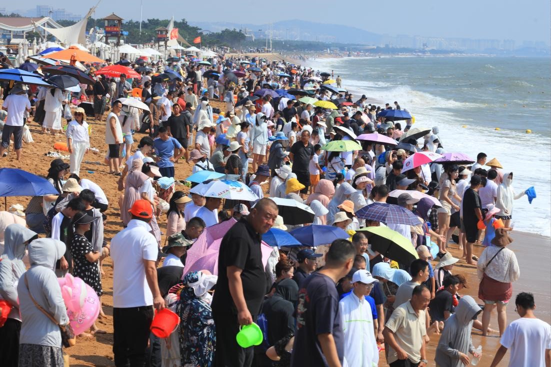 夏日海濱，沙灘上人潮涌動。張守本 攝