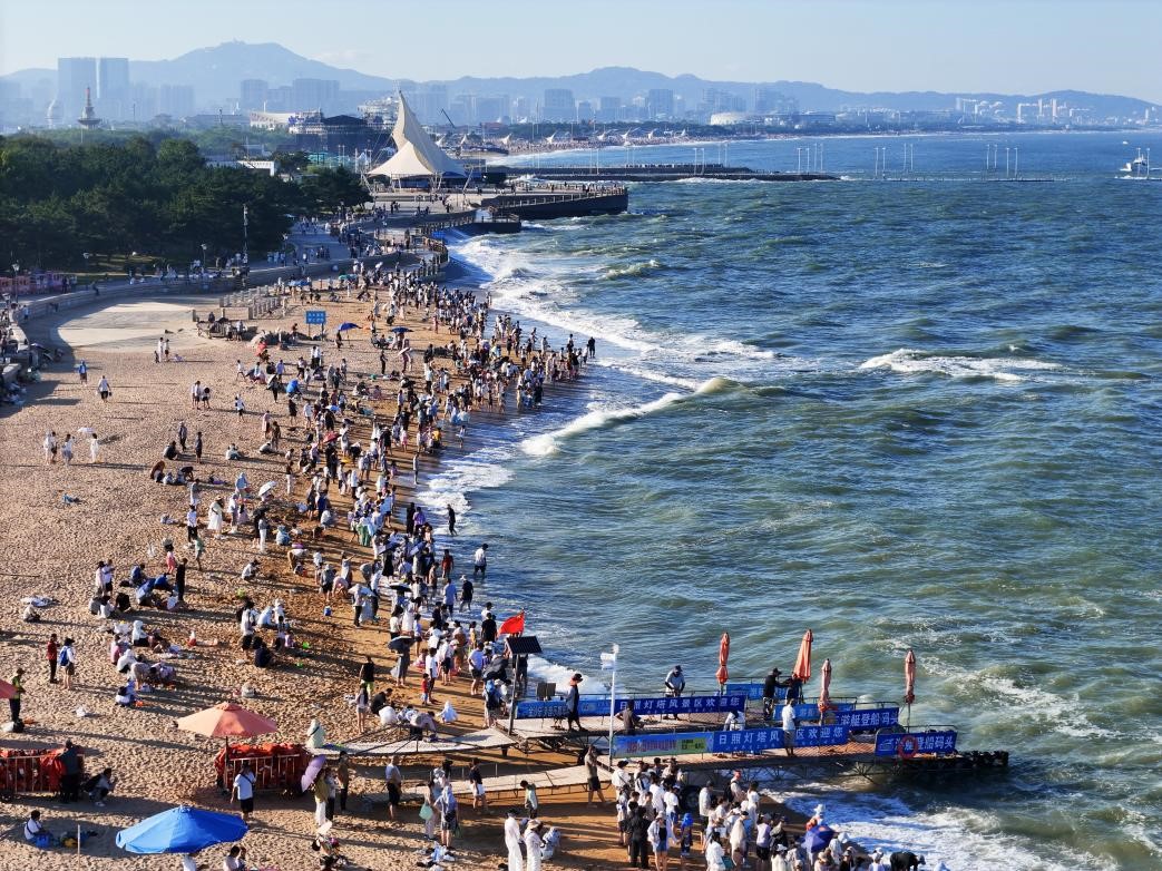 熙攘的游客們佇立在綿軟的沙灘上，等待一場海上游艇的刺激快感。張明慷 攝