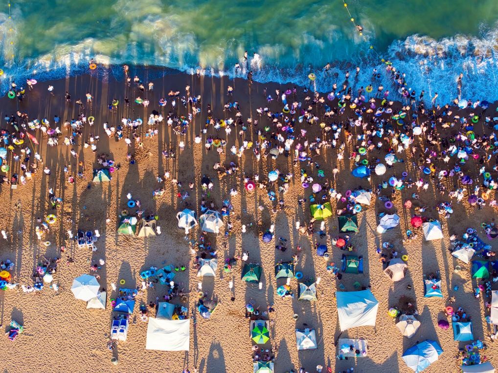 五顏六色的遮陽傘和游泳圈讓夏日海灘變成繽紛彩圖。宋年升 攝