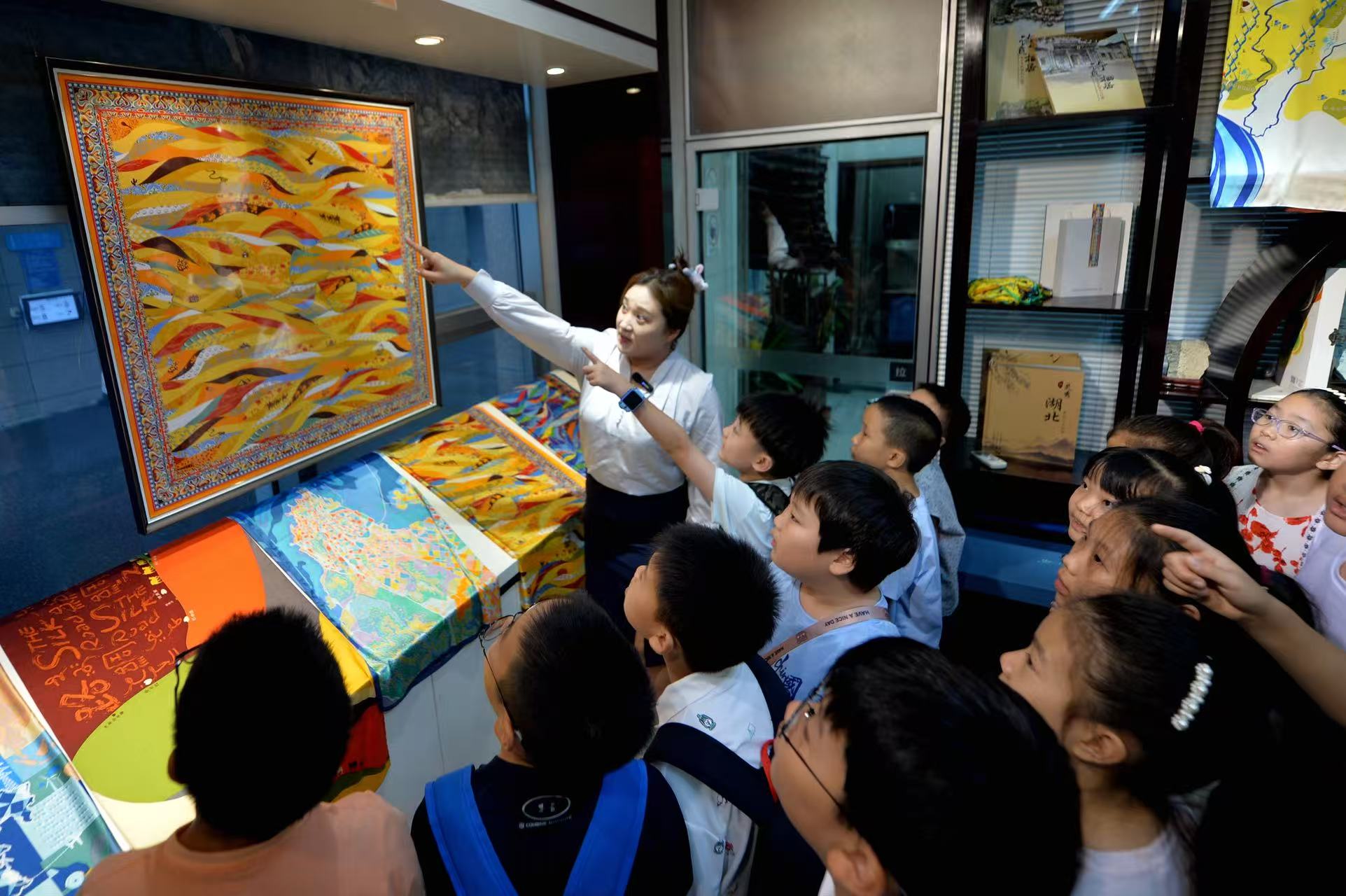 2025年8月9日，在山東省青島市勘察測(cè)繪研究院地圖文化展廳，講解員為嘉定路小學(xué)的學(xué)生介紹“絲綢之路”文化地圖。