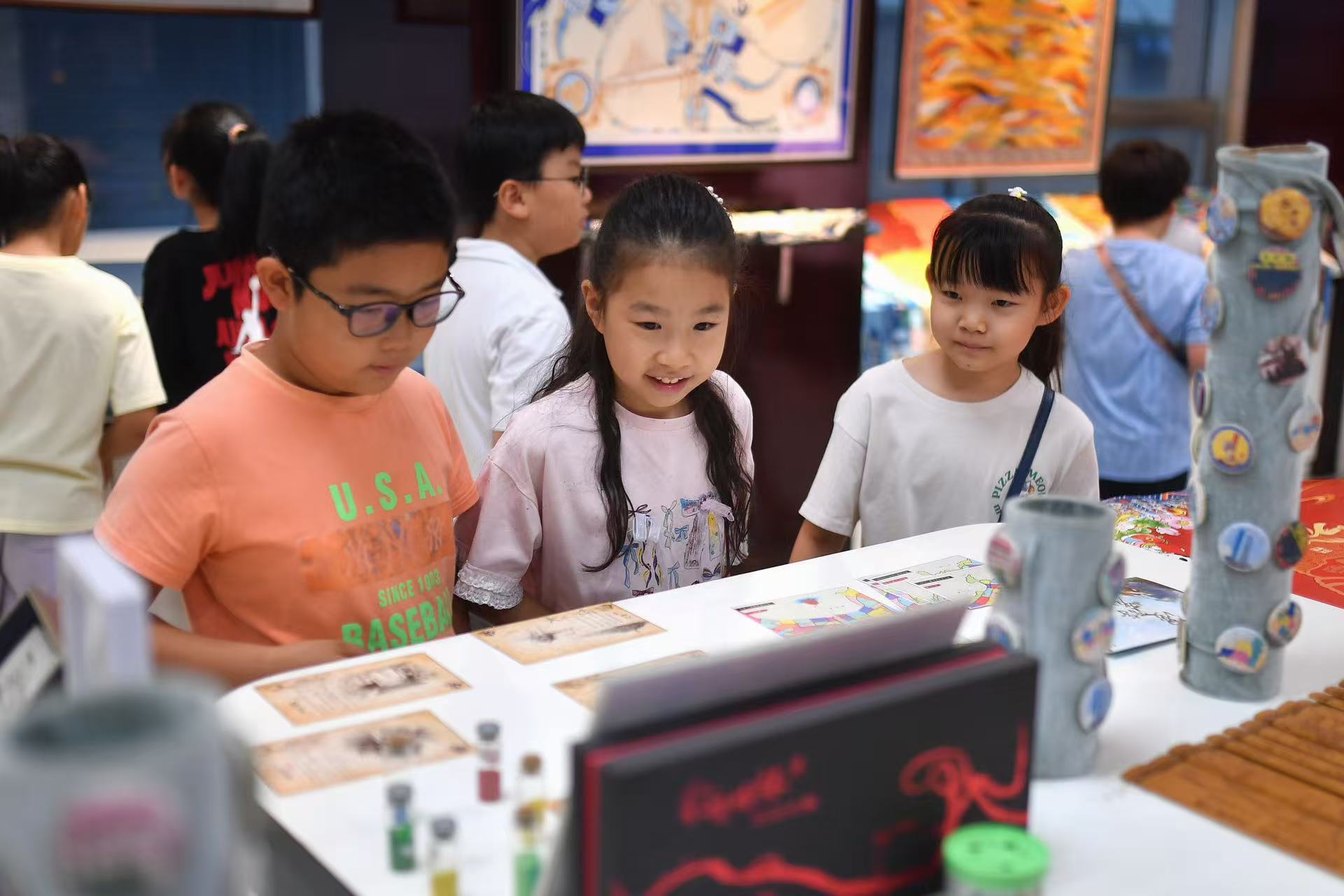 2025年8月9日，在山東省青島市勘察測(cè)繪研究院地圖文化展廳，嘉定路小學(xué)的學(xué)生在參觀“圖說(shuō)青島”展臺(tái)。