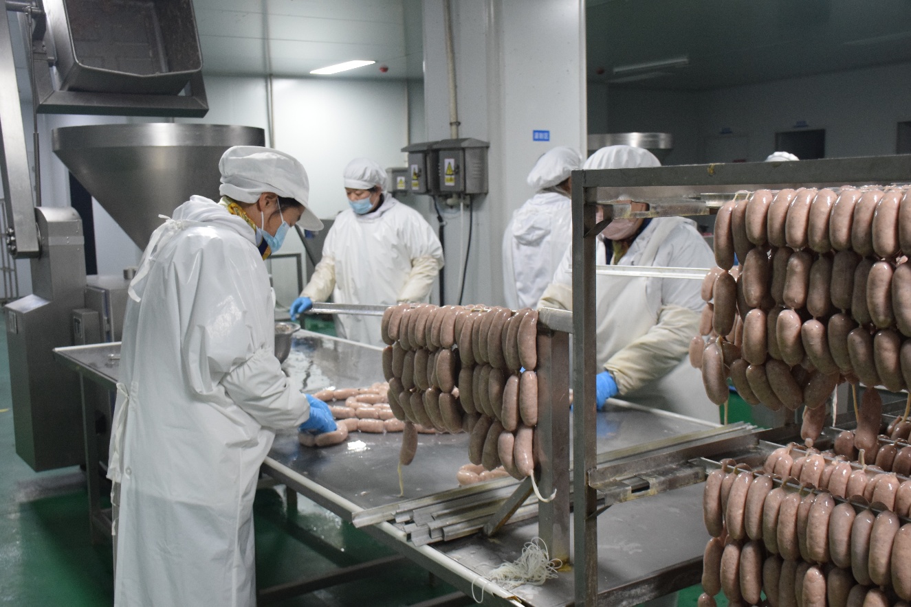 示范園食品加工廠的流水線上，工人師傅正有條無(wú)紊地制作泰山黑豬肉腸。寧陽(yáng)縣委宣傳部供圖