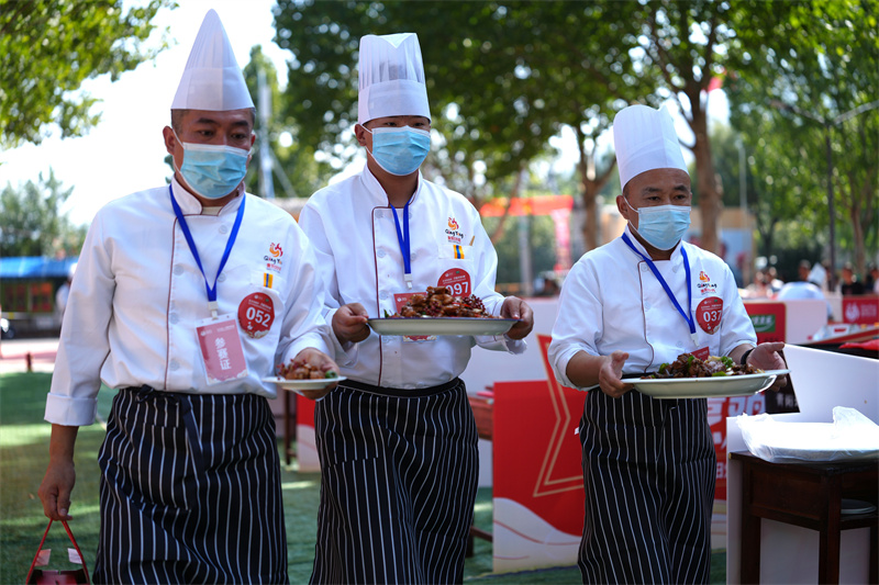 9月30日，在山東省鄒平市青陽(yáng)鎮(zhèn)炒雞品鑒中心舉行的2025齊魯烹雞大賽上，參賽選手把做好的炒雞送到評(píng)比臺(tái)。
