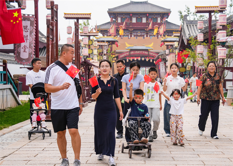 2025年10月1日，游客手持國(guó)旗在山東樂(lè)陵影視城游覽，“中國(guó)紅”成為一道風(fēng)景線。