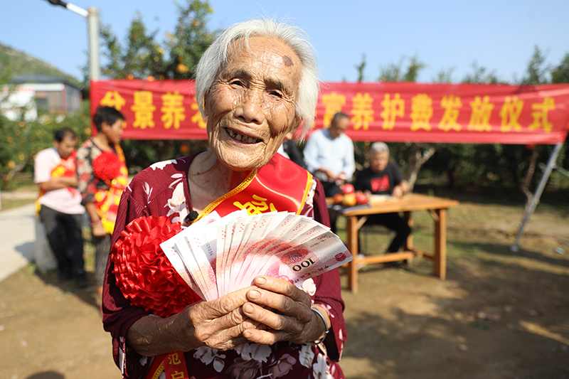 孫大娘手拿“養(yǎng)護費”，笑得合不攏嘴。孫慧攝