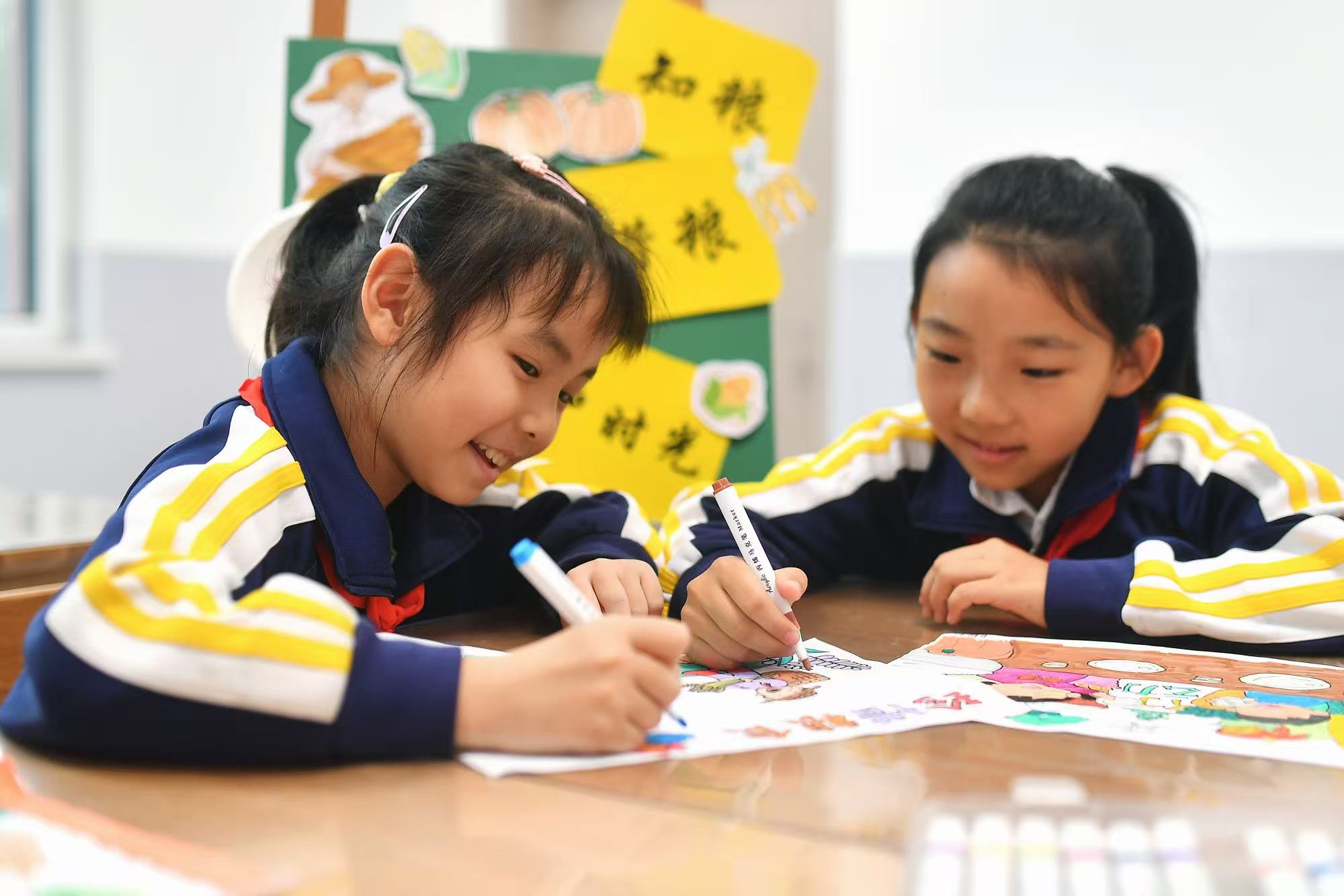 兩名學(xué)生在繪制珍惜糧食海報(bào)