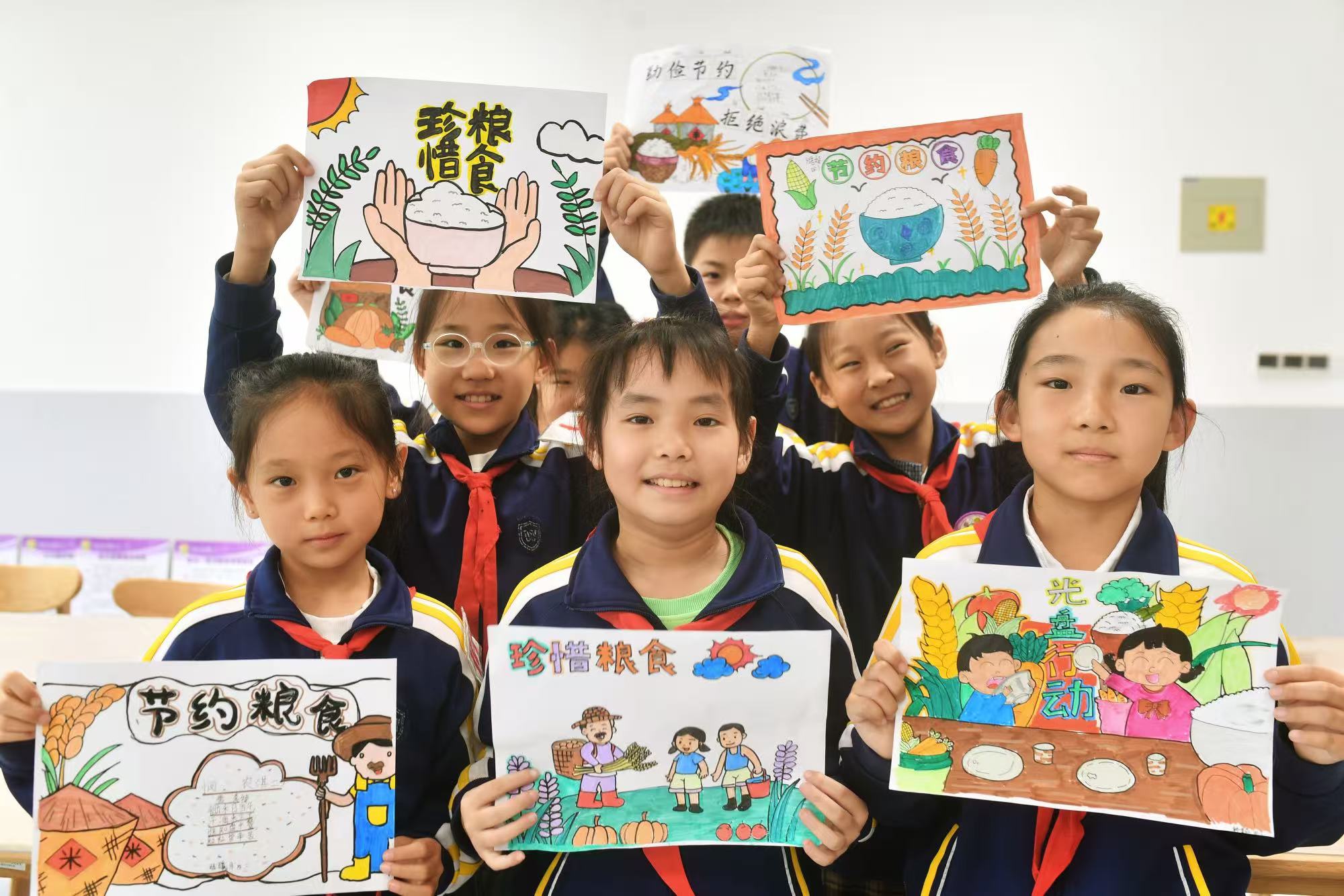 學(xué)生們展示繪制的珍惜糧食海報(bào)