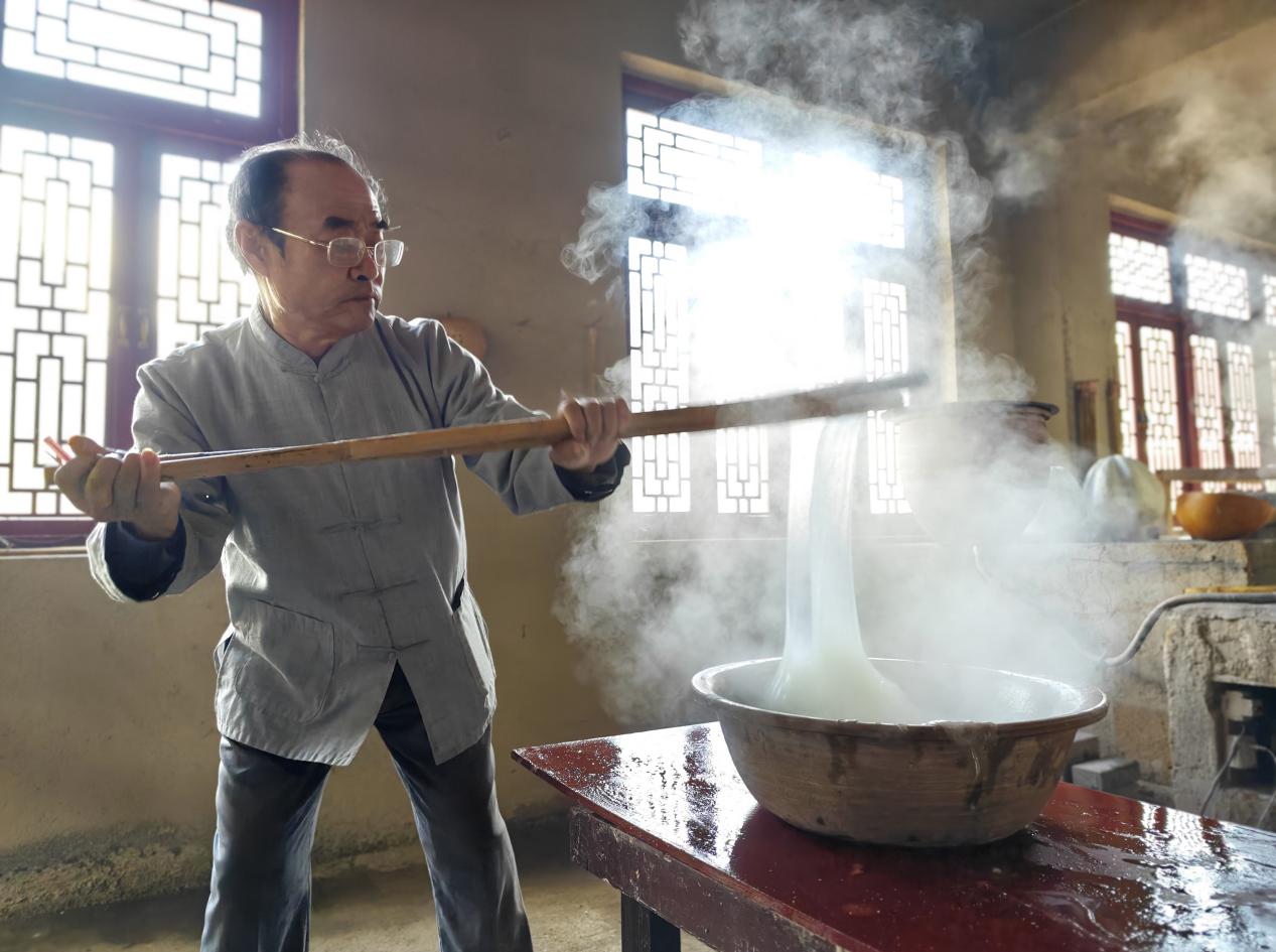 國家非物質(zhì)文化遺產(chǎn)代表性傳承人郭蘭堂演示傳統(tǒng)龍口粉絲制作中的打糊環(huán)節(jié)。周揚(yáng)攝