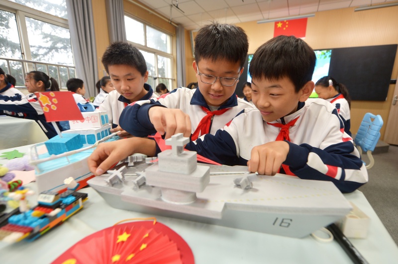 兩名學(xué)生在整理利用廢舊材料制作的航母模型。