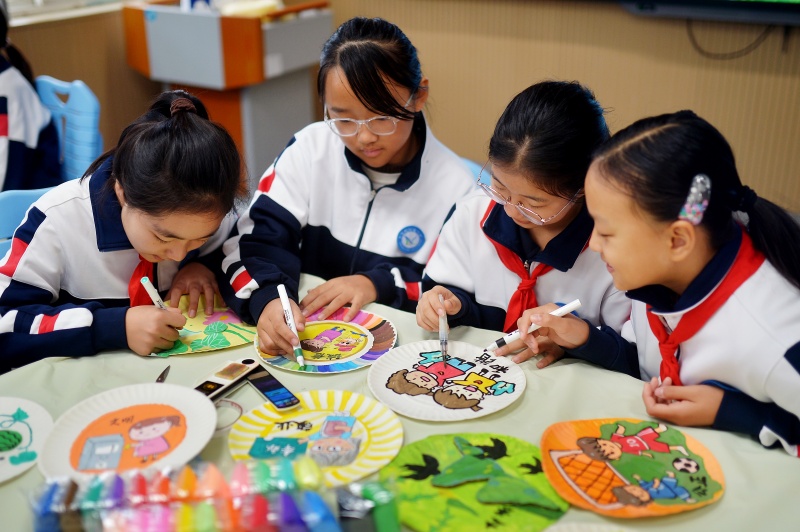 學(xué)生利用廢舊物品制作紙盤畫。