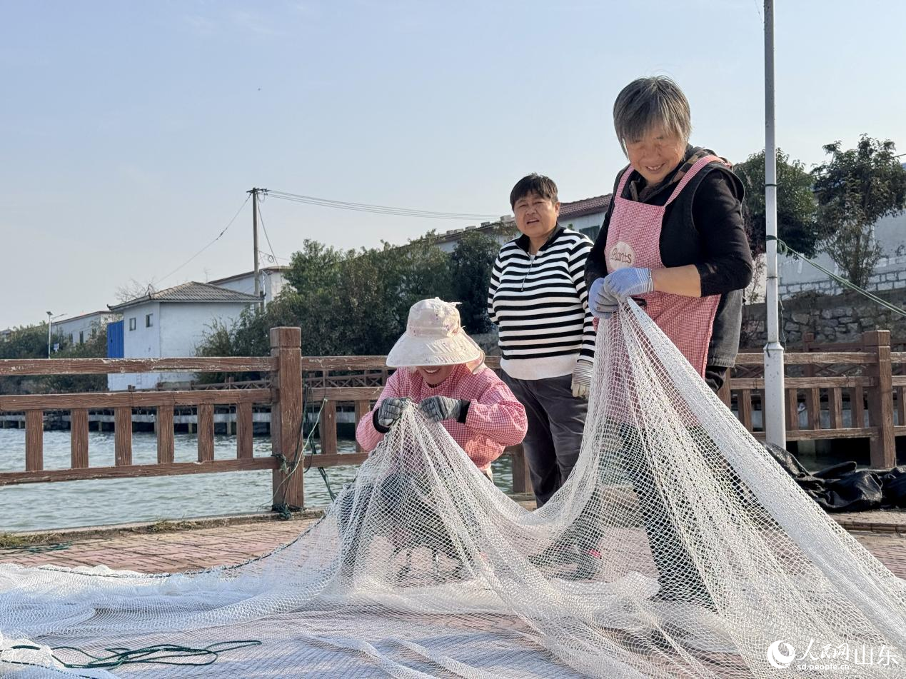 村民臉上洋溢著笑容，正在織捕魚網(wǎng)箱。人民網(wǎng) 鄭昕橋攝