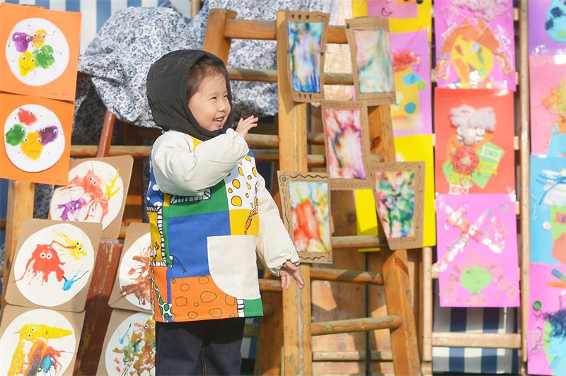 2025年11月25日，小朋友在山東省青島市市北區(qū)高安路幼兒園開展的“色彩日”主題活動上觀賞廢舊物品創(chuàng)意畫。王海濱攝