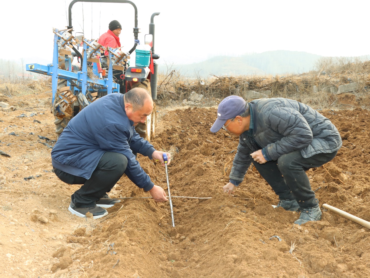 技術員和煙農(nóng)一起查看土地翻耕深度