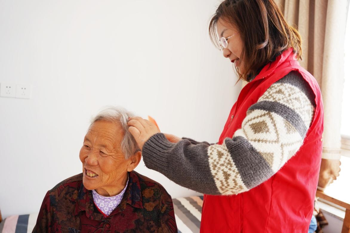 青年職工幫村民梳理頭發(fā)，村民臉上洋溢著幸福的笑容