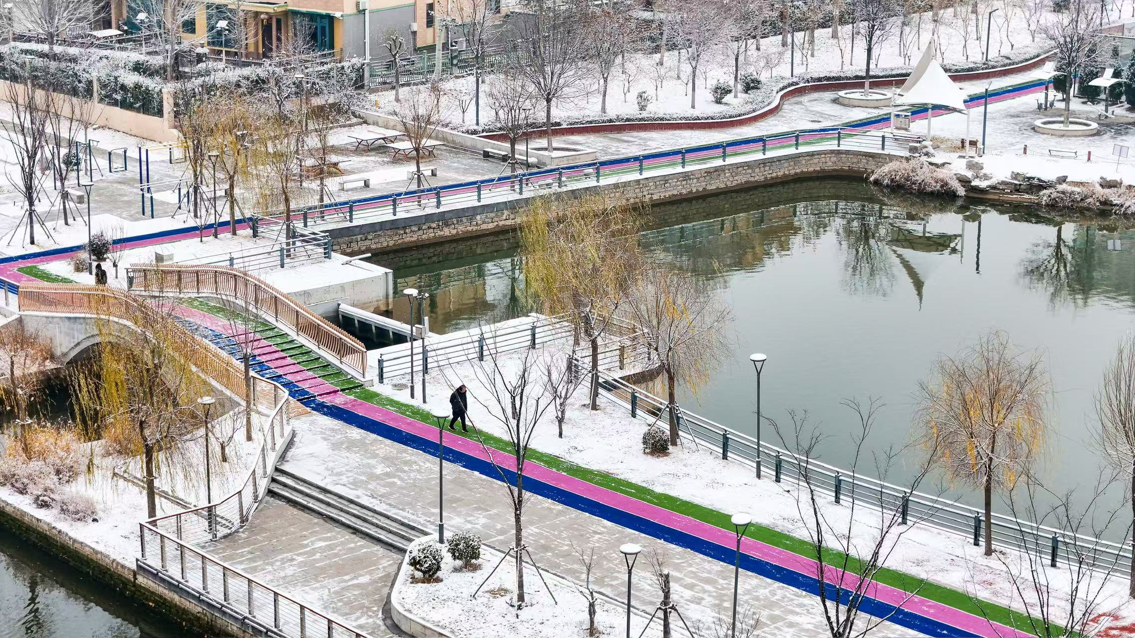 市民在山東省樂陵市玉心湖公園迎雪晨練